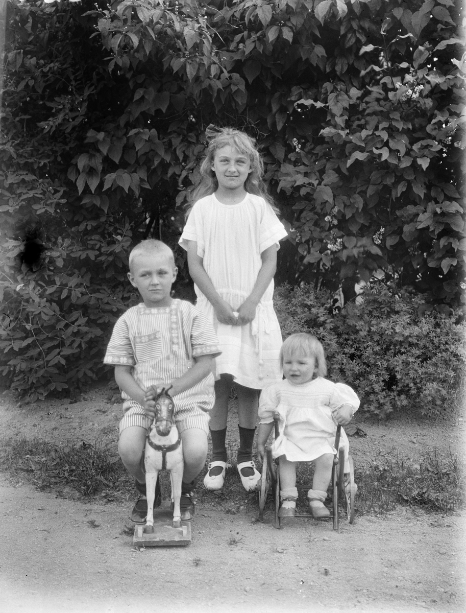 "Telins barn med trähästen" i trädgården i Fröslunda, Altuna socken, Uppland 1923