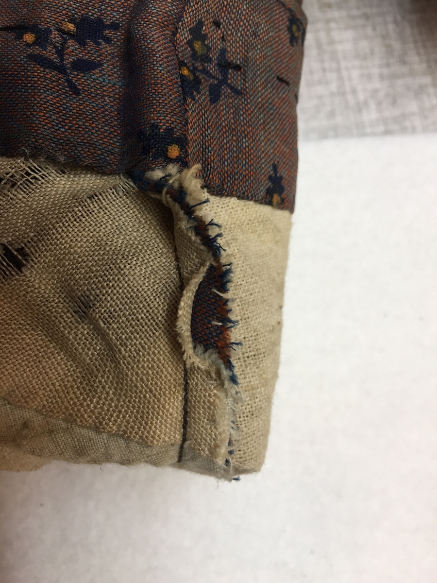 Kjole sammensydd av liv og skjørt med belte i livet med sløyfe i samme stoff. Halvull verkenstoff med trykte blomster. Sydd i Sørum i Akershus ca 1860 og senere brukt på Hamar. Skjørtet har mye håndsøm men vi ser også maskinsøm. Skjørtet er fóret med en skoning av lin i nedre kant. Det er også festet et grønt smalt bånd som slitekant. Overdelen er fóret med ufarget linstoff. Svart fløyelsbånd er festet 1,5 cm fra ermekanten.