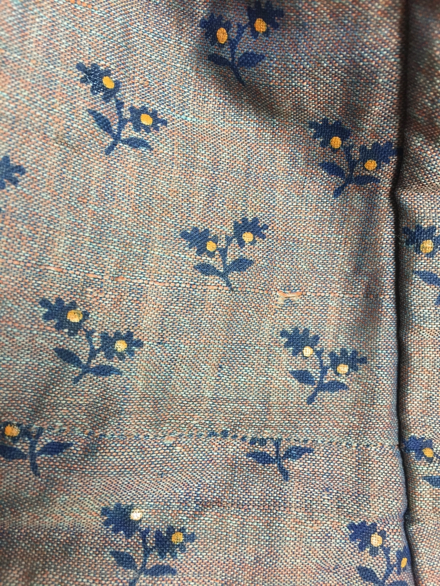 Kjole sammensydd av liv og skjørt med belte i livet med sløyfe i samme stoff. Halvull verkenstoff med trykte blomster. Sydd i Sørum i Akershus ca 1860 og senere brukt på Hamar. Skjørtet har mye håndsøm men vi ser også maskinsøm. Skjørtet er fóret med en skoning av lin i nedre kant. Det er også festet et grønt smalt bånd som slitekant. Overdelen er fóret med ufarget linstoff. Svart fløyelsbånd er festet 1,5 cm fra ermekanten.