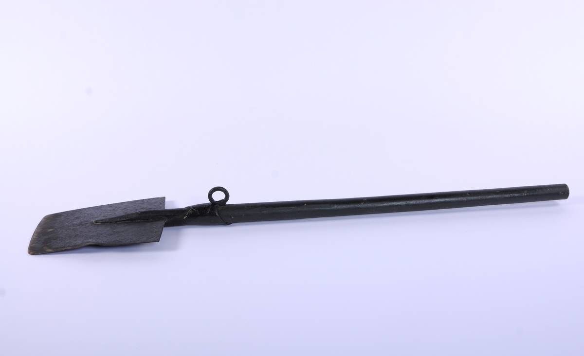 Langt, rett skaft stukket gjennom falen, ender i et spor på spadens iunderside. rett, trapesformet blad. Kraftig krok på skaftets underside, ved falen.
3 uidentifiserte stempler på bladets overside, mulig en kronet C (?)