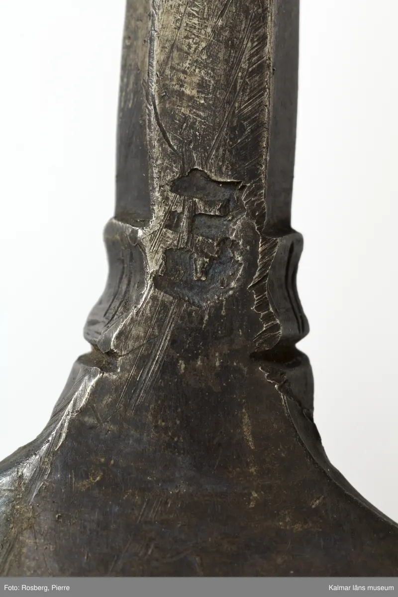 KLM 34757 Sked av metall, silver. Brett ovalt blad med sexkantigt skaft, skaftets avslutning är avbruten. I skedbladet banddekor. Rester av förgyllning, otydlig stämpel. Datering: 1500-tal?