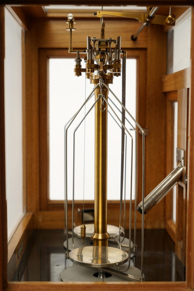 Vekt montert inn i et  monter med to dører i front og en dør på hver side. Monteret har et  "skjellet" i tre  og hvor alle sider og tak er innglasset. I fronten  er det også montert et mikroskop. På venstre side er det festet en justeringssveiv.
Under på baksiden er det skrudd fast en fot, på forsiden er det festet to justerbare føtter. Inne i monteret er det et løst speil. Alle dører har en lukkemekanisme i metall. Gulvet er antatt sort granitt. Øverst til høyre i monteren er det montert en justeringsskrue.