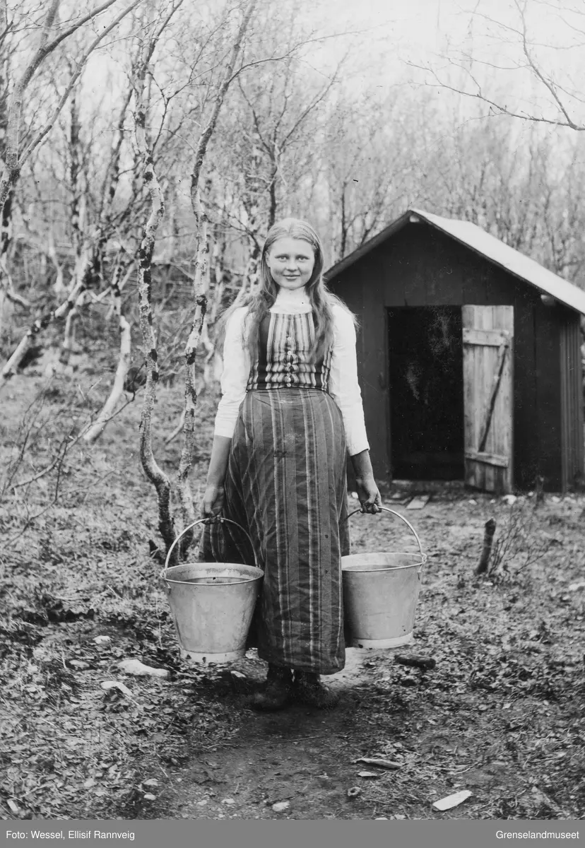 Kvenpiken Nanna Elmina Vartiainen fra Neiden var tjenestepike hos Wessels, her fotografert ved brønnhuset på doktorgården Solheim, Kirkenes 1896.