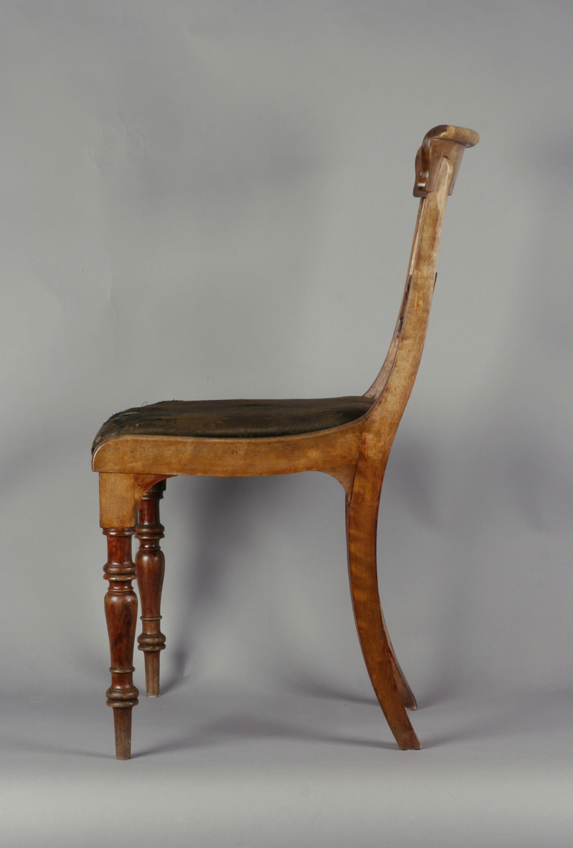 Biedermeier. Antatt bjørk med mahognybeis. Rett, noe tilbakeoverlenet, åpen rygg med utskåret midtsprosse. Det øvre tverrbrettet er glatt, noe svunget, og avrundet i hjørnene. Ingen armlener. Dreide, rette forben, lett bakoversvungne firkantede bakben. Stoppede seter, trukket med bomullsdamask. To av stolene trukket med sort trekk, to med mørkegrønt trekk.