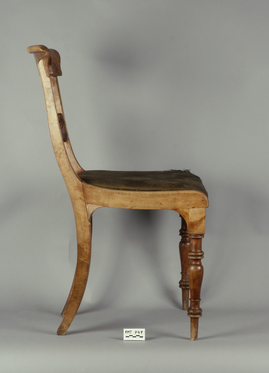Biedermeier. Antatt bjørk med mahognybeis. Rett, noe tilbakeoverlenet, åpen rygg med utskåret midtsprosse. Det øvre tverrbrettet er glatt, noe svunget, og avrundet i hjørnene. Ingen armlener. Dreide, rette forben, lett bakoversvungne firkantede bakben. Stoppede seter, trukket med bomullsdamask. To av stolene trukket med sort trekk, to med mørkegrønt trekk.