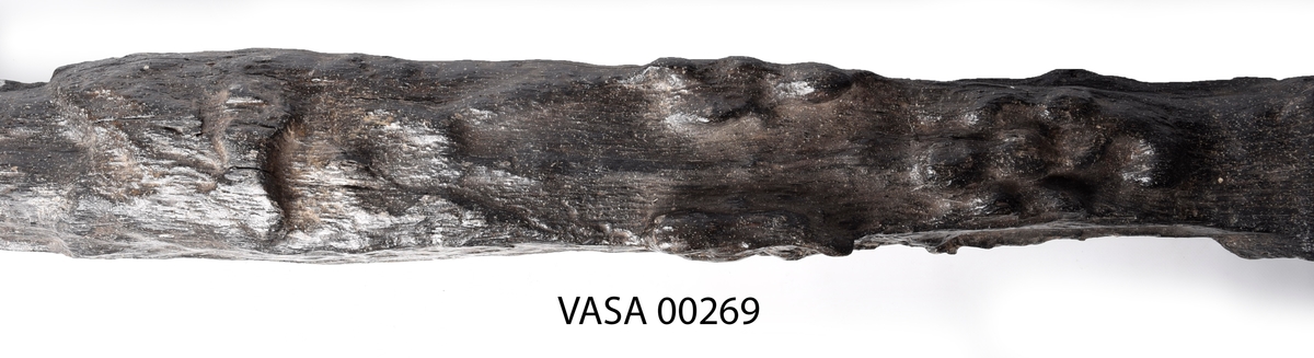 Skulpterad pilaster föreställande en herm eller möjligtvis en karyatid, under jonisk kapitäl.
Huvudet är vridet åt vänster samt prytt med en krona. Armarna hålls sträckta utefter sidorna.
Kroppen övergår i det med blad- och blomornamentik rikt sirade pilasterskaftet som smalnar av nedåt. Skaftet avgränsas genom en enkel vulst eller list från den rikt sirade och mjukt utbuktande piedestalen. Nedtill är piedestalen försedd med en bred bas. Skulpturens baksidan är slät.
Skulpturen är sliten.

Text in English: Sculptered pilaster with a Herm, or possibly a Caryatid, beneath an Ionic capital.
The head, with a crown, is turned to the left. The arms are streched out along the sides.
The body extends into the shaft of the pilaster, which tapers downwards and is richly decorated with leaf and flower ornamentation. A simple torus or batten separates the shaft from the richly decorated, softly bulging pedestal that has a broad base. The back of the sculpture is smooth.
The sculpture is worn.