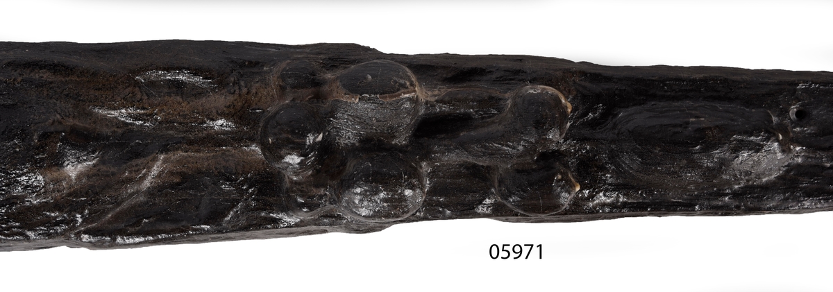 Skulpterad pilaster utformad som en karyatid med långt hår, troligen placerad under ett joniskt kapitäl.
Huvudet är vridet åt vänster. Höger arm är sträckt utefter sidan. Vänster arm är böjd och i handen håller figuren ett okänt föremål.
Pilasterskaftet är upptill prytt med en maskaron med bred, öppen mun och nedtill med en tung fruktfeston. Det nedåt avsmalnande pilasterskaftet avgränsas från piedestalen av en enkel vulst eller list med uppdragna kanter. Piedestalen är hög och jämnbred samt prydd med ett litet huvud och avslutas nedtill med en förtjockad bas. Skulpturens baksida är slät.
Skulpturen är kraftigt sliten och nött med finare detaljer utplånade.

Text in English: Sculpted pilaster with Caryatid with long hair under what is possibly an Ionic capital.
The head is turned to the left, the right arm is streched along the side, the left arm is bent and the hand holds an unknown object.
The shaft of the pilaster is decorated above with a mask with a broad, open mouth, below is a heavy festoon of fruit. The shaft tapers downwards and is divided from its pedestal by a simple torus or batten with drawn-up edges. The pedestal is high and even in width and decorated with a small head. It terminates at the bottom in a thickened base. Its back is smooth.
The sculpture is much worn, with finer details obliterated.