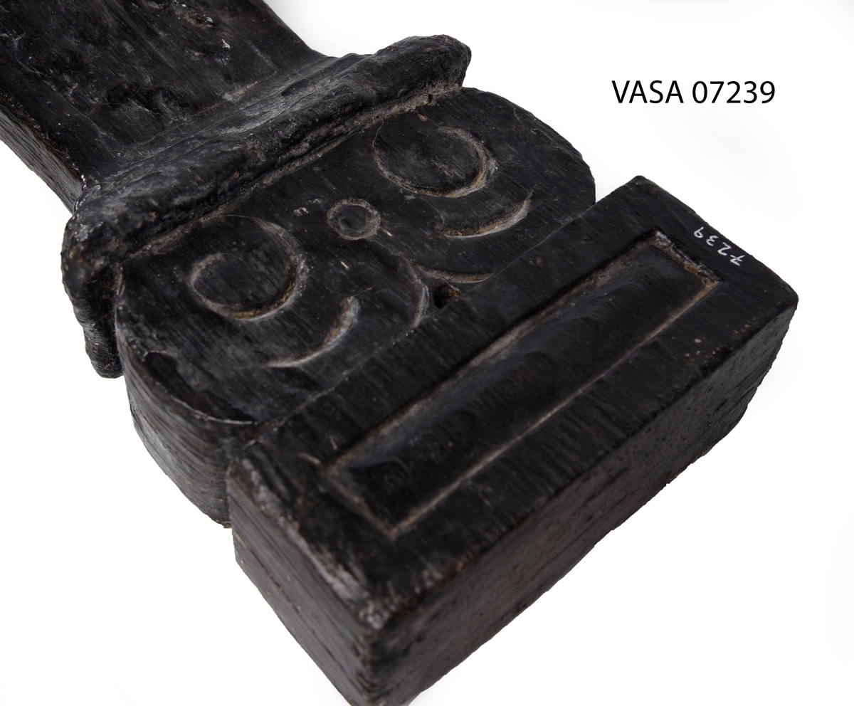Liten skulpterad pilaster, utformad som en karyatid eller möjligen en putto. Figuren har långt hår och ett knubbigt ansikte, omgivet av en bred krage. Det nedåt avsmalnande pilasterskaftet är dekorerat med akantusblad. Nedtill avslutas pilastern av en rikt profilerad och dekorerad sockel. Skulpturens baksida är slät.
Skulpturen är sliten, främst den övre delen.

Text in English: A small carved pilaster, with a caryatid or probably a putto. The figure has a chubby face, long hair and a broad collar. The lower part of the pilaster is decorated with acanthus leaves. The caryatid stands on a richly profiled and decorated socle. The back of the sculpture is smooth.
The sculpture is worn.