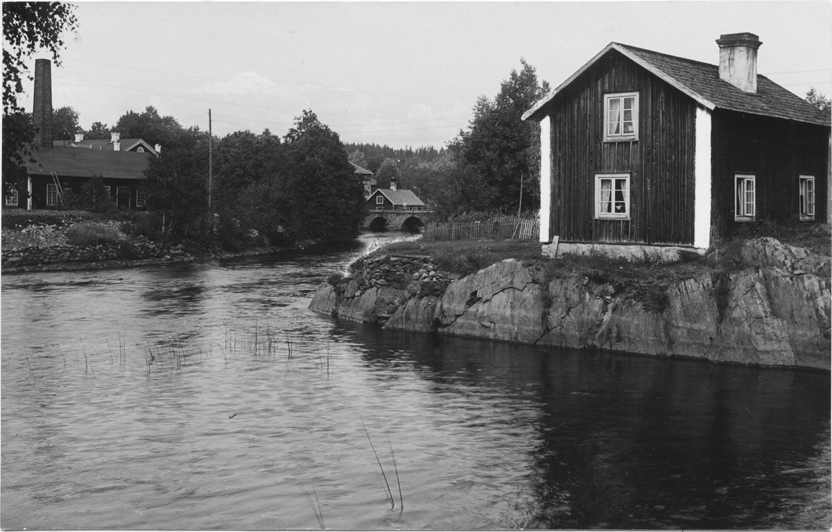 Emm ån nedanför fallet. Till vänster laboratoriet. Till höger maskinistbostaden. Klefva Bruk. Tillhörande Ädelfors Bruks AB.