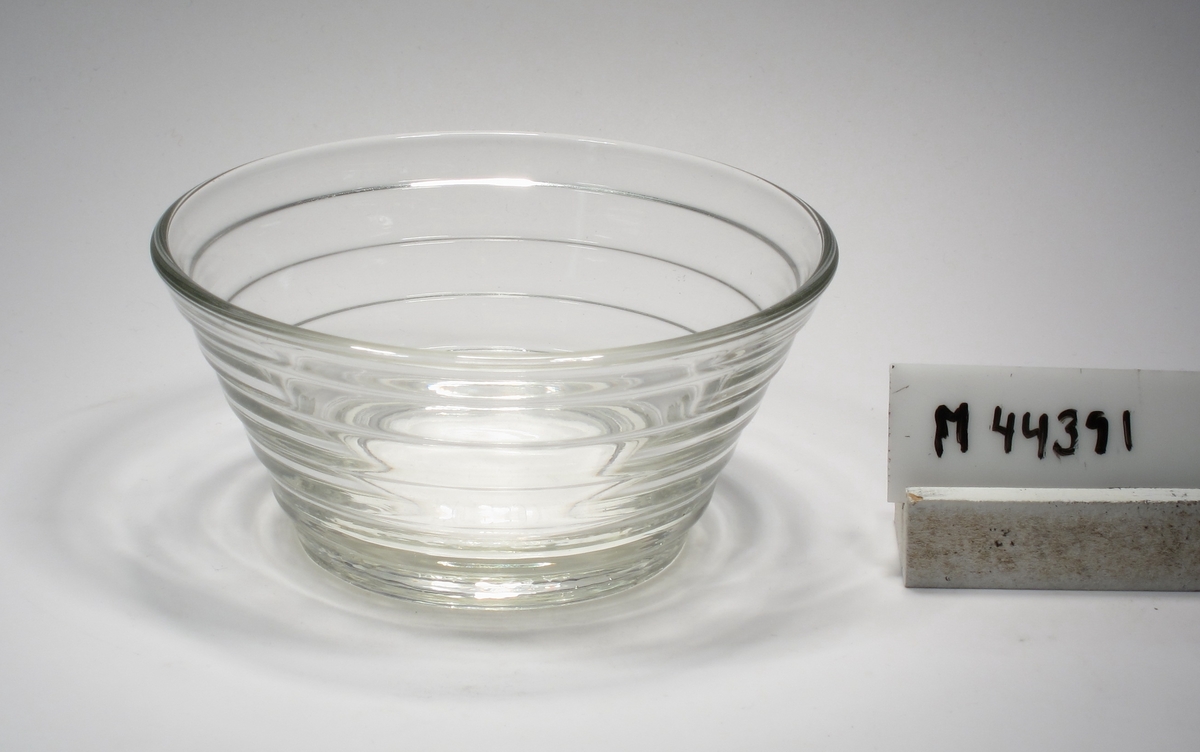 Skål av pressglas.
Beskrivning: Konoid, sex stycken avsatser som smalnar av nedåt.
Färg: Ofärgat klarglas.
Mått: Ovan anges höjd och övre diameter. Diameter botten: 65 mm.
Inskrivet i huvudkatalogen tidigast 1988.
Funktion: Skål