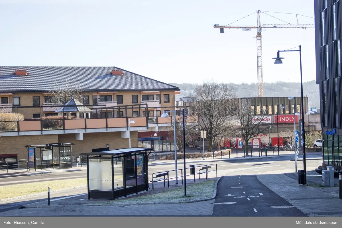 Vy från Storgatan mot Brogatan, år 2015. Till höger skymtas höghuset på Storgatan 32A. Platsen där den vänstra "Mölndals Centrum"-skylten står, blev senare Ulla Jacobssons Plats. Bild 4: till vänster ses Bergmansgatan. Dokumentation av platsen innan rivning och nybyggnation.