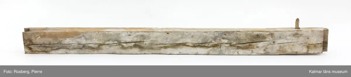 KLM 17275:4:2. Vägg, del av. En timmerstock tillhörande en innervägg. En trädymling sitter i stocken. På båda sidor bevarade fragment av bemålning, troligen från 1600-talet. På båda sidor måleri i grått, grönt och vitt med rombiska eller runda figurer i svart och rött. På ena sidan även rester av påspikade tapeter.