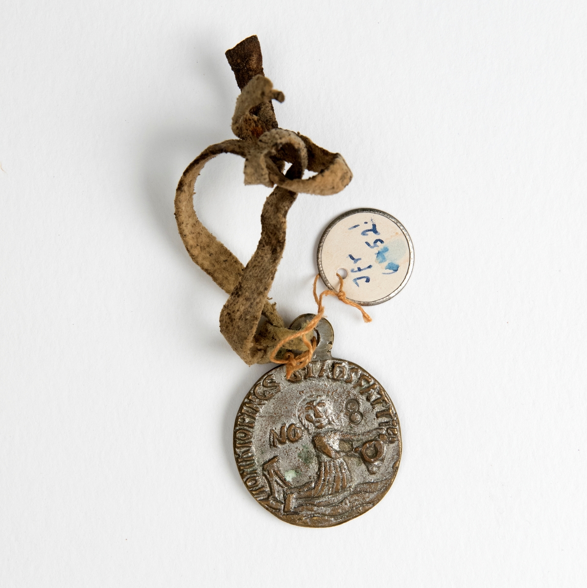Gjutet runt märke av vit metall med text i relief på båda sidorna: "Jonkiopings stads [...] No 8", samt ett motiv av en sjöjungfru. Enligt accessionskatalogen 1904 står det felaktigt "No 11". Ett ljust läderband är knutet i märket. En liten rund pappbricka är vidhängd märket, märkt; "Jfr 6452!"