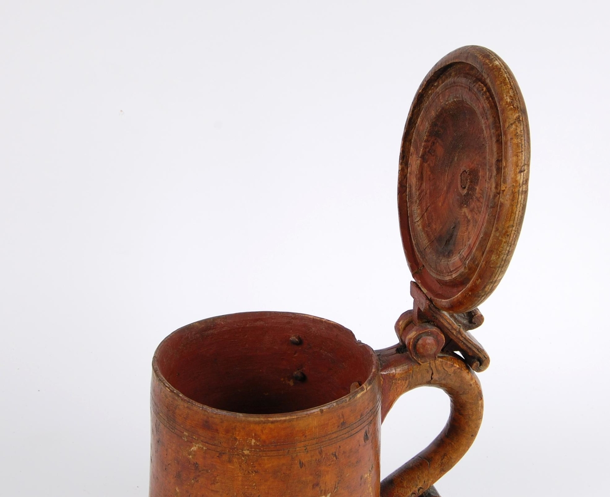 Kanne av dreid valbjørk. Lokket med dreide ringer. Bladformet lokkåpner. Hank med utskjæringer, ender i en spiss med bladdekor. Korpus med dreide ringformete bårder øverst,  fire målemerker innvendig.