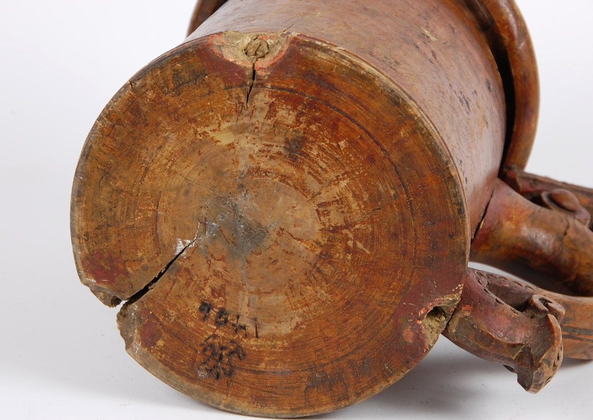 Kanne av dreid valbjørk. Lokket med dreide ringer. Bladformet lokkåpner. Hank med utskjæringer, ender i en spiss med bladdekor. Korpus med dreide ringformete bårder øverst,  fire målemerker innvendig.