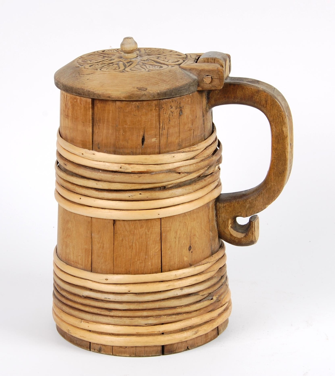 Kanne av trestaver. Lokket med seks hjerteformete utskjæringer. Lokkgrep kuleformet med flat topp. Korpus med syv gjorder oppe og åtte nede. Hanken skåret ut av en stav.