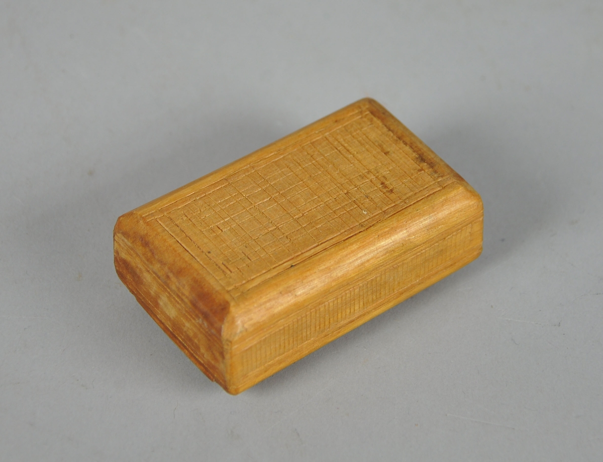 Eske av tre, med skyvelokk. Lokk og underside av eske er dekorativ utformet med treskjæring.