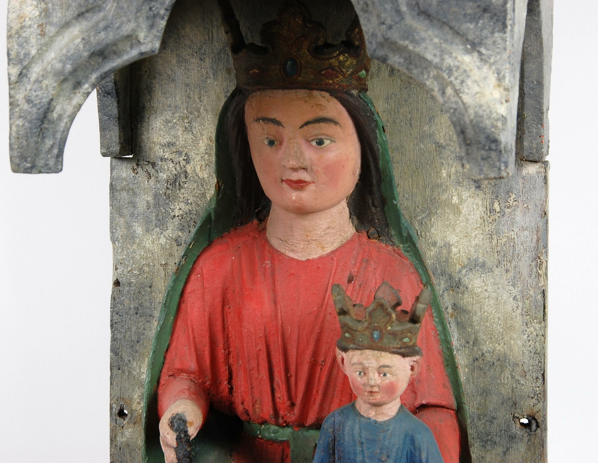 Madonna med barnet sittende på en trone under en baldakin. På toppen av baldakinen er tre gullfargete knotter, og under Madonna er det en slange som kveiler halen. Skulpturen har senere maling. Maria har rød kjortel og grønn kappe, mens Jesusbarnet har blå kjortel.