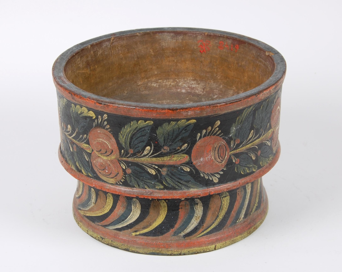 Smørkopp av dreid tre. Koppen har rosemalt dekor med blomstermotiver i ulike farger, røde kanter oppe og nede, hull i bunnen. Stetten har rosemalte skrå stiper.