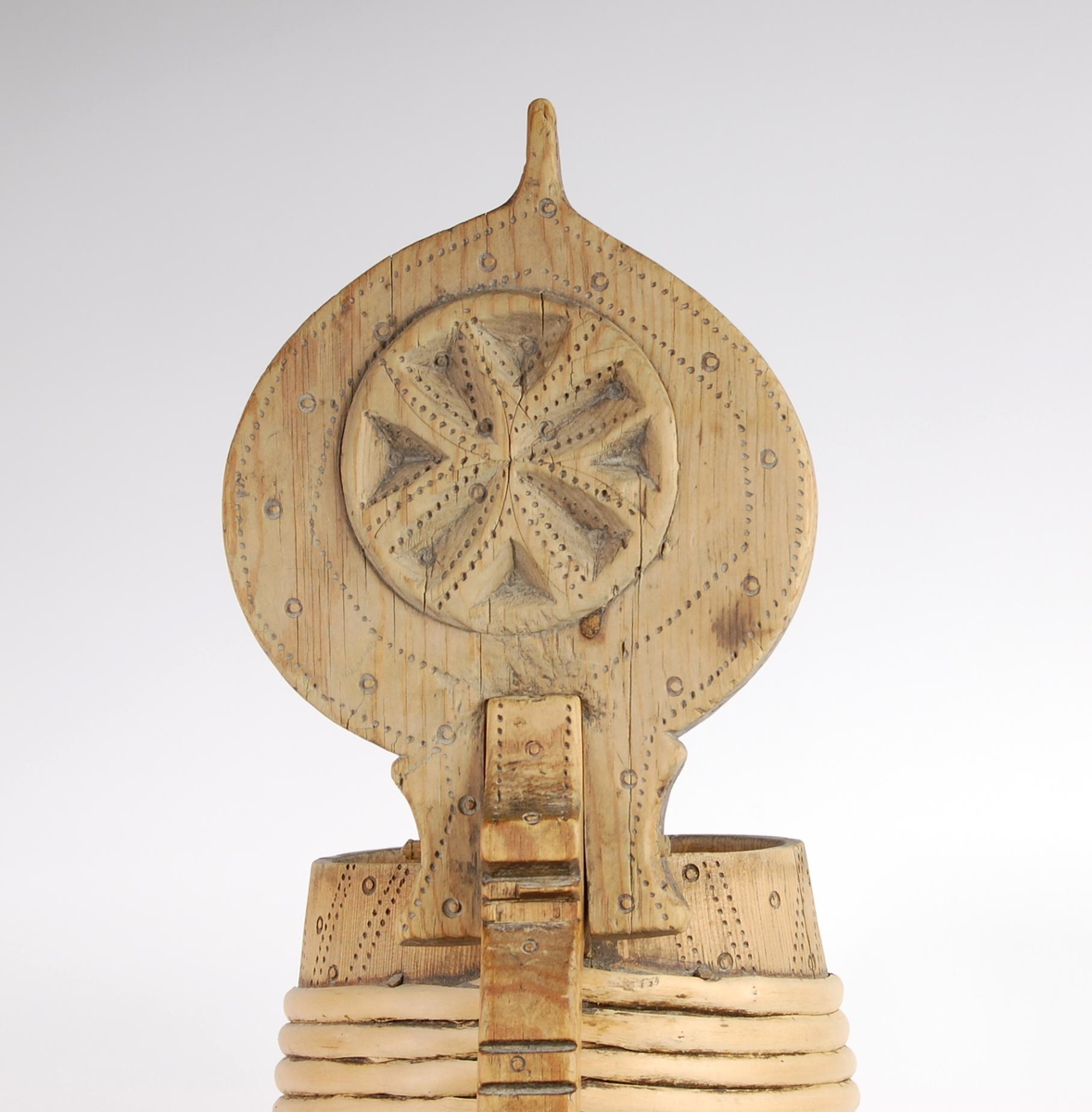 Kanne av trestaver. Lokket har utskåret firebladrose og svidekor i form av rundinger og prikker. Hanken går i ett med en av stavene, har dype hakkformete utskjæringer og noe svidekor i form av rundinger og prikker. Korpus har fire gjorder oppe og ni nede (opprinnelig har det også vært to gjorder midt på. Videre har korpus mye svidekor i form av rundinger og prikker. Underside har innsvidd innskrift