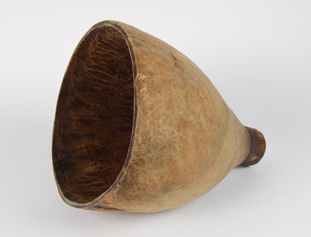 Trakt av gran. Tilnærmet rund form. Tut med rund åpning og merker etter en ring.