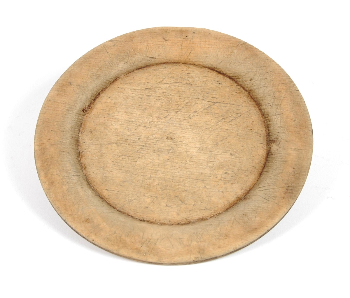 Tallerkner av dreid bøk. Sirkelrund med svak opphøyet ytterkant. Buemerke på ene siden.