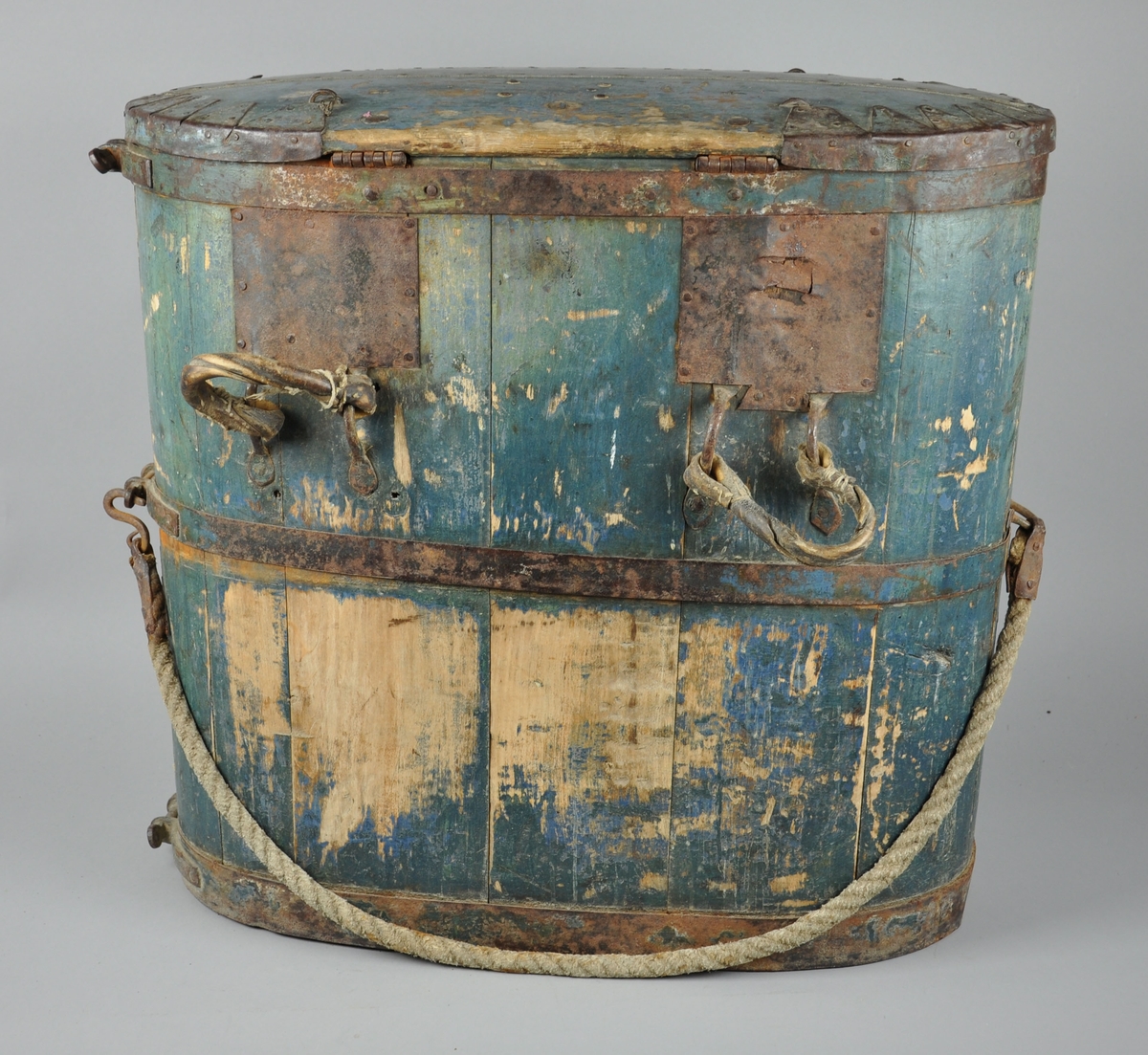 Kløvbomme lagget med 15 staver. Treverket og deler av metallet er blåmalt, lokket er i stor grad armert med metall. To håndtak av lær på baksiden. På baksiden er det også en stoffreim, festet i metallhåndtak på sidene. På framsiden sitter det en lås med innskriften 'secure'

På baksiden har mye av malingen flasset av.
På nedre framside er det en sprekk i treverket.