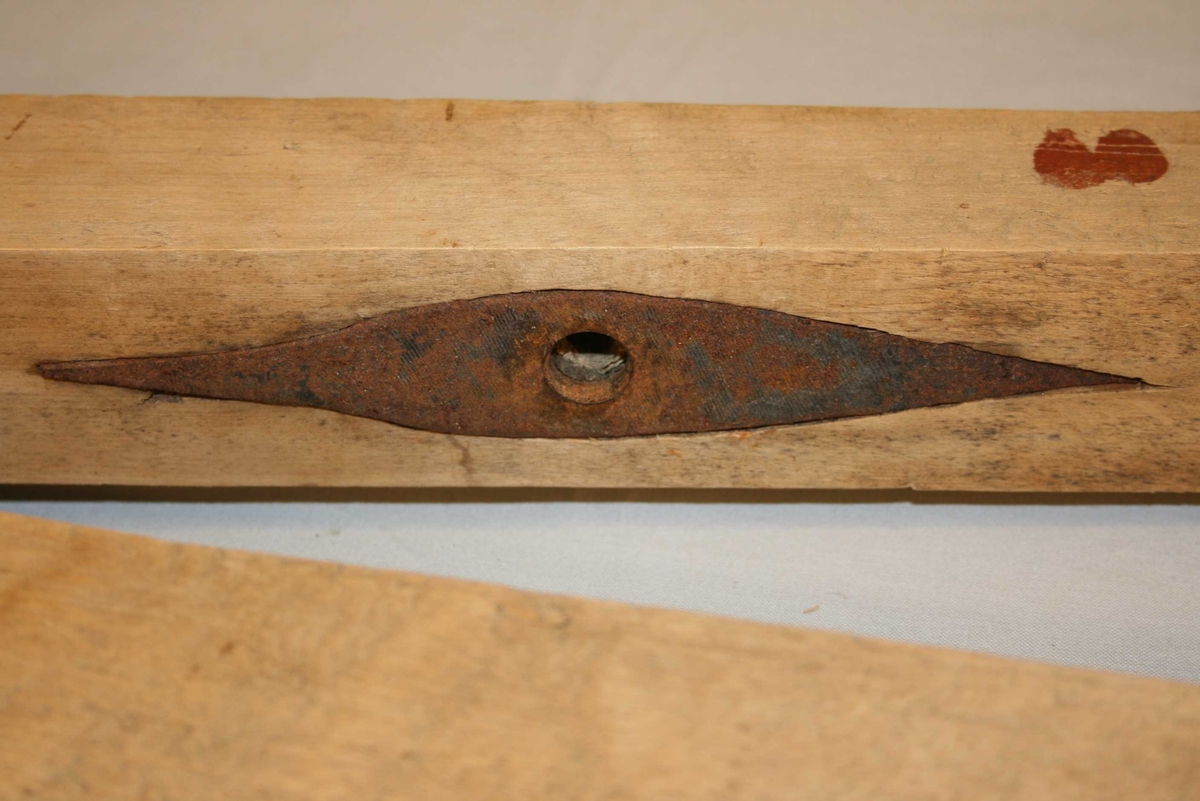 To trestykke feste saman i eine enden så dei kan pressast mot kvarandre, styrepinne. Hol gjennom det trestykket som kan least, midt på, jernbeslag på undersida. Større hol, ca. 1 cm djupt, midt i mot i det andre trestykket.