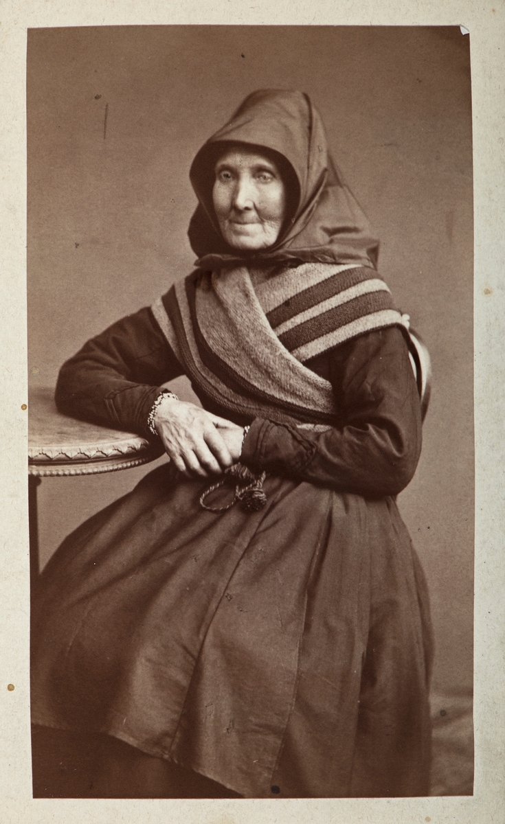 Kari Arnestad, Aamodt. Portrett. Folkelig motedrakt, høglue med skaut, og med bundingstørkle over skuldre og brystkasse.
Kari Olsdatter Arnestad, 1819-1881. Født på Arnestad Store i Åmot, ugift. Bodde hos sin svoger Anders Mikkelsen og søster Ingeborg Olsdatter på Arnestadsveen i Åmot i folketelling for 1865, bosatt på Stenvigen i Stor-Elvdal ved sin død.