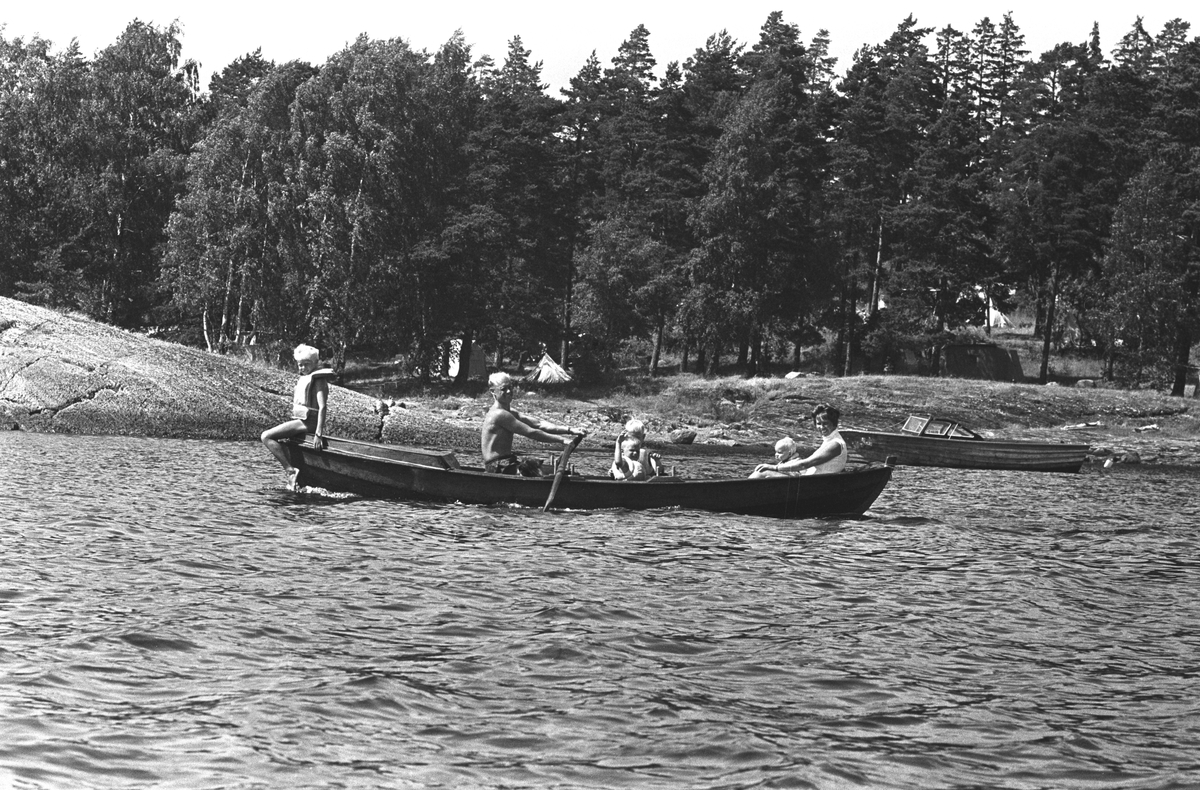Erik Damman, reklamekonsulent fra Oslo, ferierer i båt med familien i Oslofjorden. De skal ro 10 - 12 mil i løpet av 8 - 10 dager, og går i land på små holmer som fjorden har mange av.  Fra høyre Ragnhild Damman og minstemann Jaran (1,5). Midt i båten Are (8), Brede (5). Erik Damman og Rein (10) til venstre.