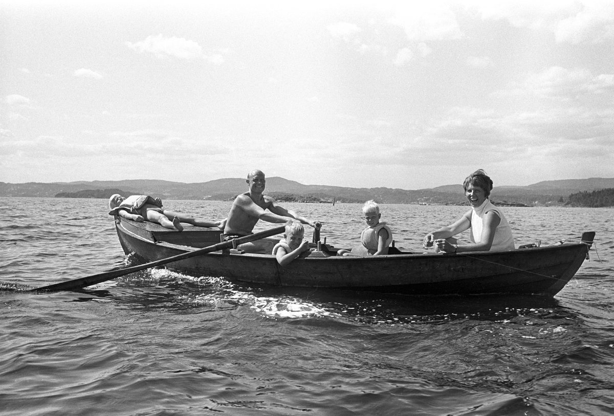 Erik Damman, reklamekonsulent fra Oslo, ferierer i båt med familien i Oslofjorden. De skal ro 10 - 12 mil i løpet av 8 - 10 dager, og går i land på små holmer som fjorden har mange av. Erik Damman ved årene. Ragnhild Damman sammen med Are (8) og Brede (5). Rein (10) ligger på soldekket forut.