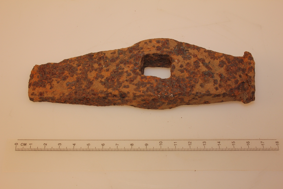 Rektangulær form. Jamt smalande i eine enden. Andre enden er butt, brukt til å slå mot harde gjenstandar. Kvadratisk hol på midten.