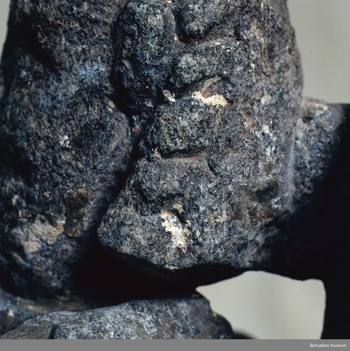 Stenskulptur av täljsten från Svarteborgs kyrka. Den helige Olof sittande i tronstol med högt ryggstöd. Han bär livbälte och mantel, en murkrona på huvudet, möjligen ett relikvarium i höger hand och håller vänster hand om skägget. Skulpturen är starkt eroderad.

Ur handskrivna katalogen 1957-1958: Olav d. helige, täljsten, Svarteborg. M: H. 41, största Br. 32,5 cm; krona och mantel, i höger hand spiran, vänster griper om skägget; sittande på en tronstol m. armstöd och högt ryggstöd, på alla håll smalnar stolen av uppåt. Starkt sliten.

Ur Katalog 1. Uddevalla Museihistoriska samlingar, svenska avdelningen. A. Yngre föremål. Upprättad av Knut Adrian Andersson 1916:                                                                                                                              No 34. Bild i täljsten av Olov den Helige. Yngre medeltiden, räknad till 1550. Förvarats i Svarteborgs kyrka under namnet "Kung Rane". Skänkt av församlingen år 1860-70-tal till Uddevalla museum. Förvaras ovanpå Medeltidsskåpet i sydvästra rummet.

Presenterad i  Uddevalla Museums tryckta katalog 1869 under rubriken 
F] Saker från yngre Medeltiden, räknad till 1550.
N:o 1. Bilder af S:t Olof i sten från Svarteborgs kyrka.

1861-1870 1 Arkeologiska och Etnografiska samlingarna U-a Museum D4A 1
Ur Gåvobok1864:
Svarteborgs församling:
Kristusbild af träd samt fragmenter af en Granit- [överstruket] Täljstensbild, enligt sägen föreställande Kung Rane, hvilka begge setat [överstruket] [oläsligt tillägg] i Svarteborgs kyrka. 
Tillagd kommentar av intendent Knut Adrian Andersson; Olof d. Helige troligen.

Se foton på föremålet i Uddevalla museums kyrkliga utställning 1920, UMFA54467:0089.
Tillstånd, se Vårdblankett.