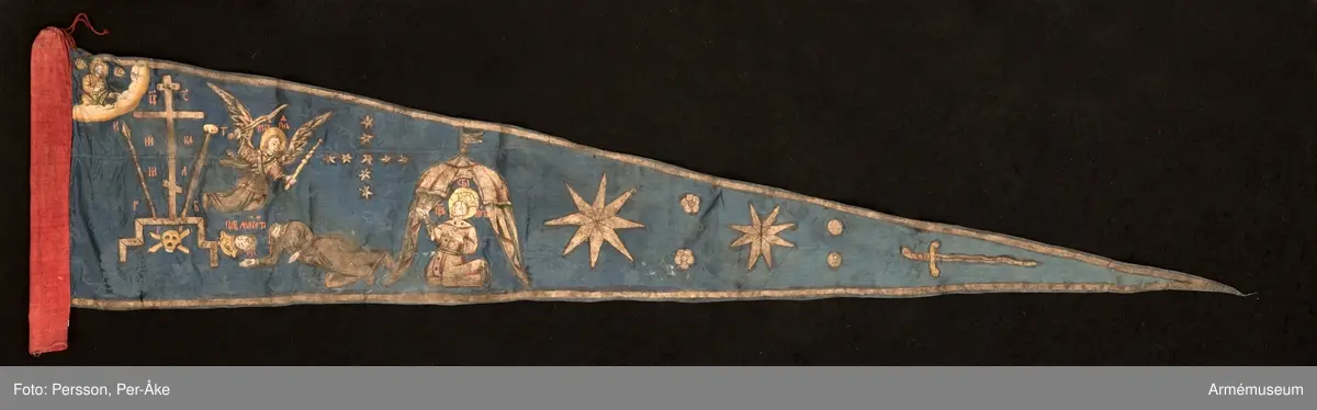 Duk av blå kinesisk sidendamast med målad dekor. Motivet föreställer den romerske kejsaren Konstantins vision av ett kors i skyn kvällen innan slaget vid Pons Mulvius år 312 e Kr mot Maxentius. En ärkeängel med svärd i handen (Gabriel?) svävar över den halshuggne Maxentius. Denna händelse ses som förklaring till att kristna kors började användas på militära fanor. Närmast stångsidan är också ett Golgatakors avbildat. Över detta syns ett moln där Kristus är avbildad. 
Strumpa av rött linne.