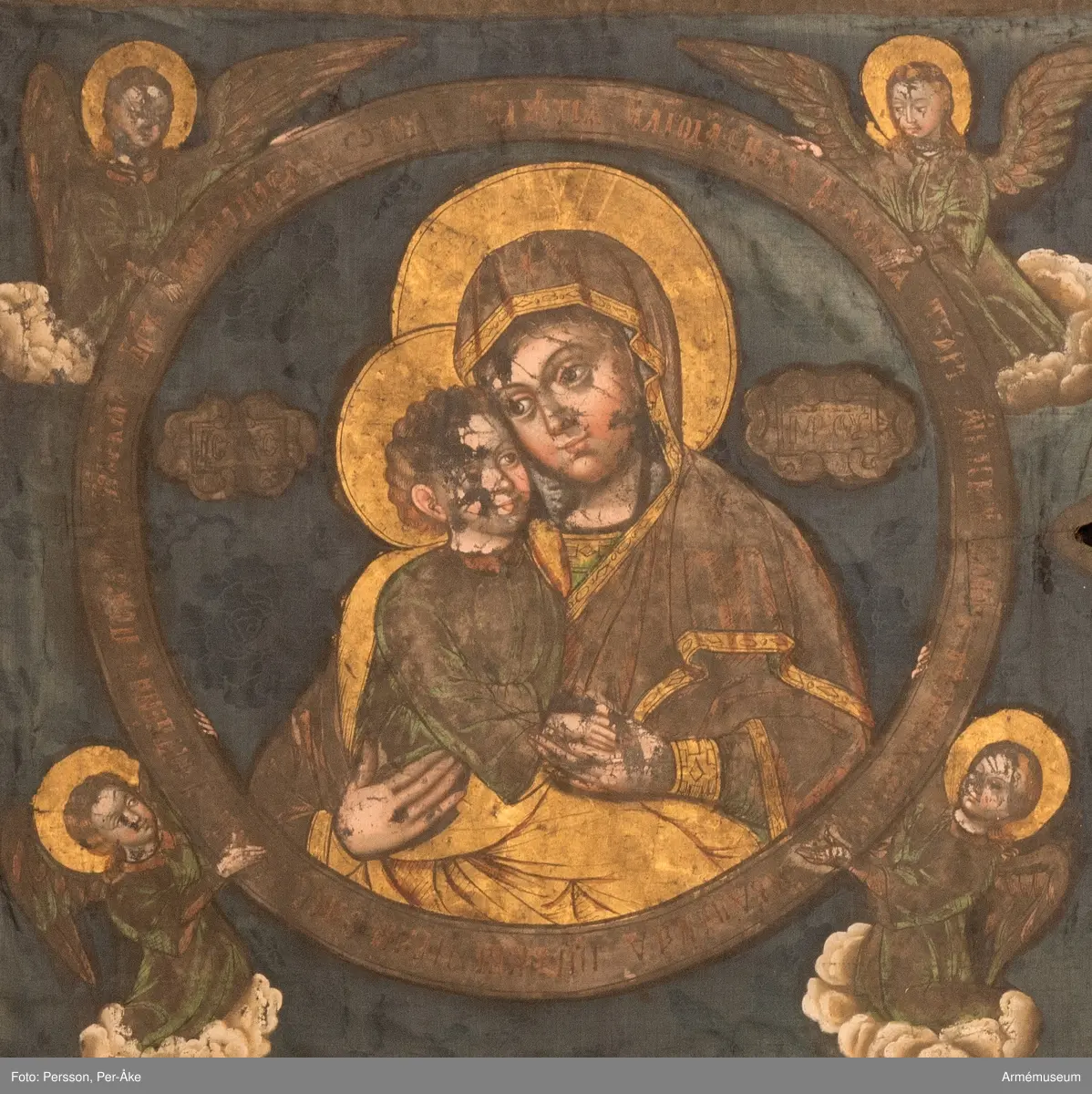 Tvåtungad duk av blå kinesisk sidendamast. Strumpa av rött kläde. Motivet målat med guld- och silverfärg.
Maria och Jesusbarnet återges i den komposition som kallas "Ömhetens Gudsmoder". Den av änglar burna medaljongen pryds av rysk inskrift som i översättning lyder: "Över dig, Fader, gläds var skapad varelse, änglarnas skara och människosläktet. Du ger ljus åt de rättrognas kyrka. Vi, dina barn, lovsjunga dig, milde Fader."
Motivet är lika på båda sidor men av stilen att döma är de målade av olika konstnärer.