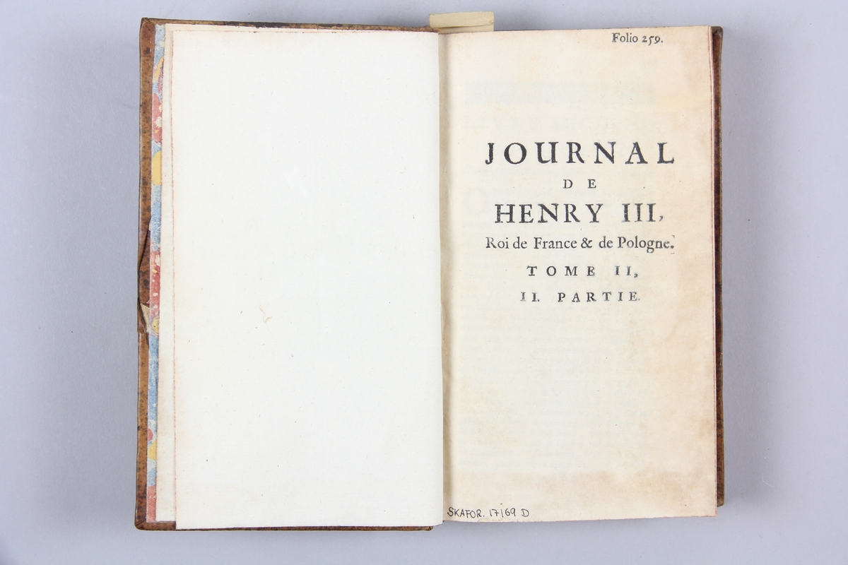 Bok, helfranskt band, "Journal de Henry III", del 2:2, tryckt i Köln 1720. Skinnband med guldpräglad rygg med fem upphöjda bind. Titelfält med blindpressad titel och volymens nummer, rödstänkt snitt. Marmorerat papper på pärmens insida. Etikett med samlingsnumret.