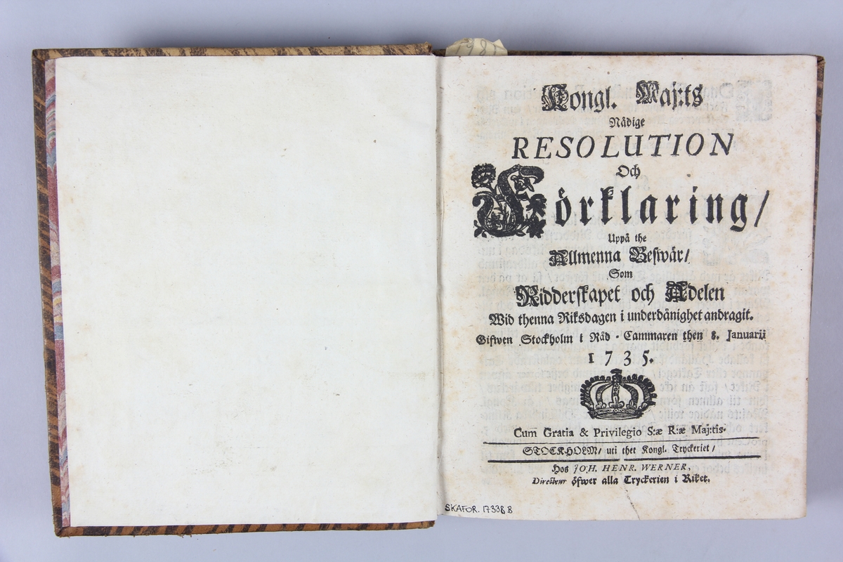 Bok, helfranskt band "Kongl. Maij:ts nådige resolution och förklaring...", tryckt i Stockholm 1735.
Band av skinn med guldpräglad dekor med rygg i fem upphöjda bind, blindpressat fält med titel och med ägarinitaler. påklistrad pappersetikett med samlingsnummer. Marmorerat papper på pärmarnas insidor. Rödstänkt snitt.