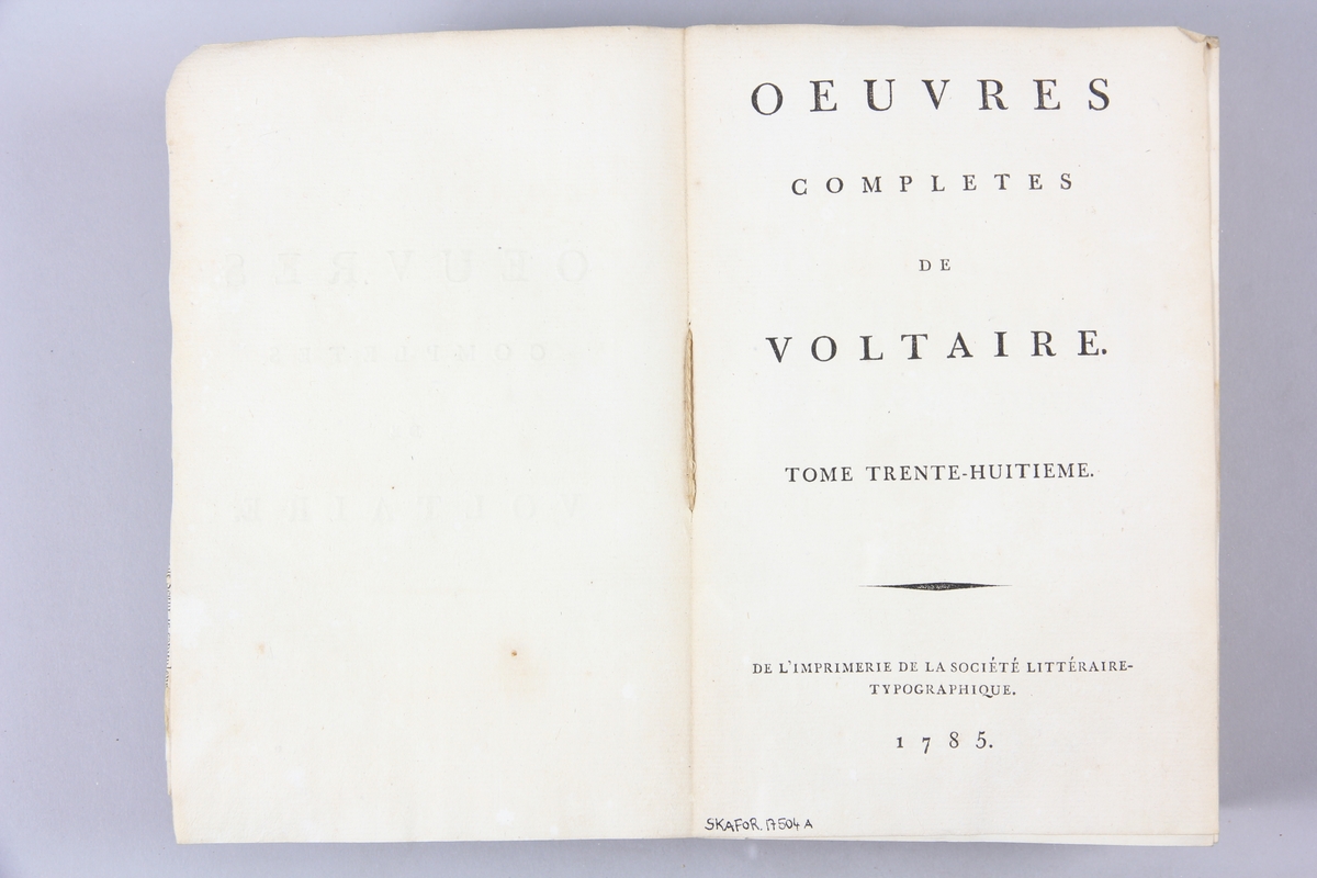 Bok, pappband,"Oeuvres complètes de Voltaire." del 38, tryckt 1785.
Pärm av gråblått papper, på pärmens insidor klistrade sidor ur annan bok, skurna snitt. På ryggen pappersetikett med tryckt text med volymens namn och nummer. Ryggen blekt.