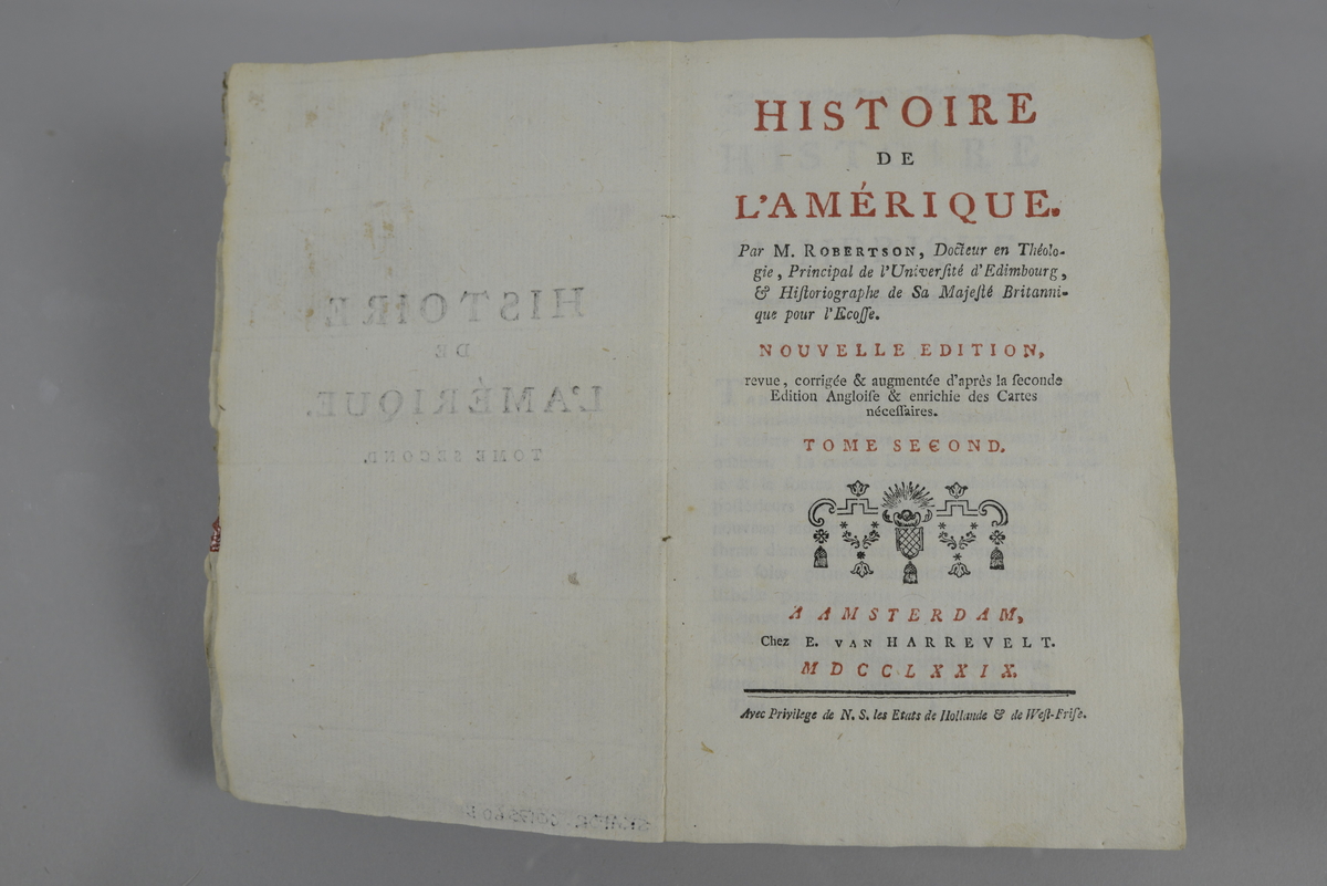 Bok, pappband, Histoire de l´Amerique, del 2, skriven av M. Robertson, utgiven 1779 i Amsterdam.
Pärmen klädd med grått papper. Med skuret fläckat snitt. På ryggen tryckt etikett med nummer samt oläslig påskrift. Med karta. På pärmens insida påskrifter med tusch samt rester av rött lack.