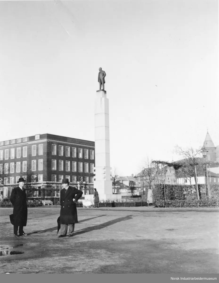 Menn ved statue på søyle i Bergen.