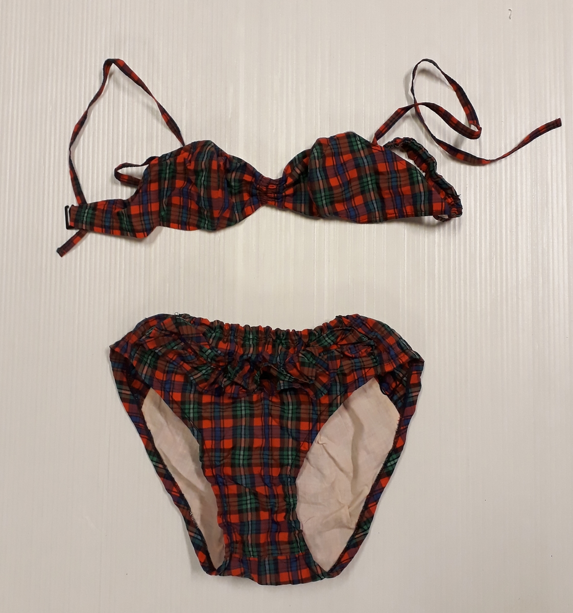 Blommig säck av galontyg innehållande badkläder: rutig bikini, blå badbyxor och blå/rosa bikinibyxor. Medföljde vid insamlingen av Vegkryssaren TERTIA.
