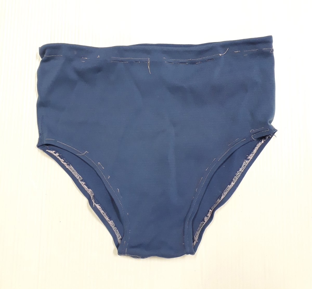 Blommig säck av galontyg innehållande badkläder: rutig bikini, blå badbyxor och blå/rosa bikinibyxor. Medföljde vid insamlingen av Vegkryssaren TERTIA.