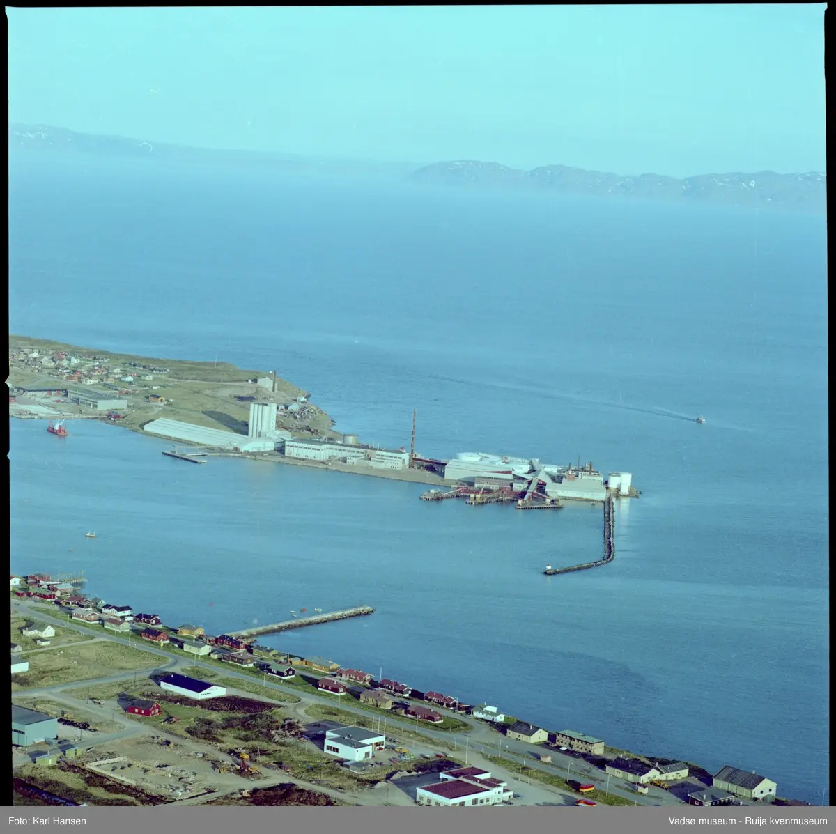Vadsø, Vadsøya. Flyfoto av Vadsø sildoljefabrikk. Fabrikken ble påbegynt 1952 og sto ferdig til første produksjon vinteren 1953, modernisert og utbygd 1976-1980. Siste produksjonsår var 2009. Kilde: www.kystogfjord.no (artikkel av Bjørn Hildonen 28.10.2011).