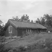 Storstugan till hemmanet Österhagen i Bankekinds församling. Sittande i dörröppningen skymtar gårdens ägare, Johan Albin Stein. Vy från sydväst.