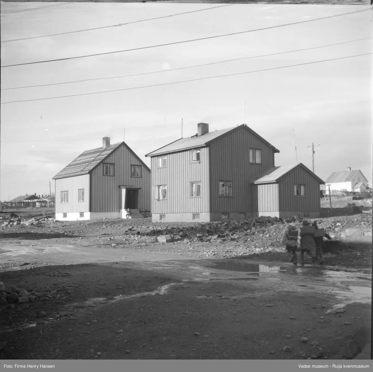 Vadsø, Gjenreisningshus. Tre barn med ryggsekker i gata i forgrunnen