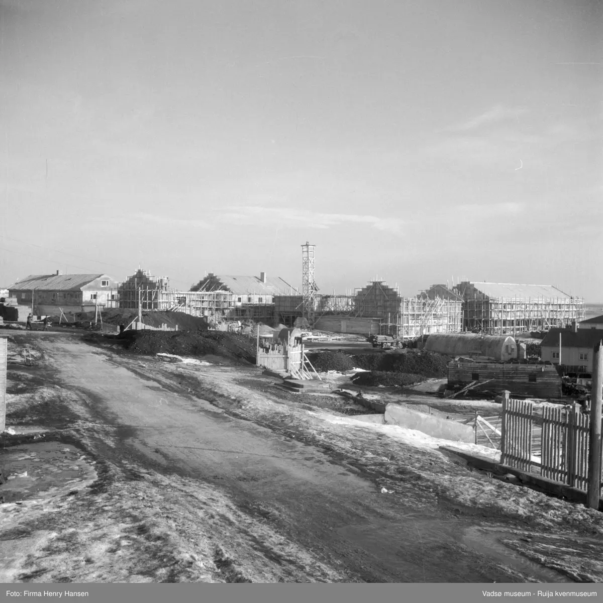Vadsø sentrum. Gjenreisninga av Sentrum i full gang. Forretningsbyggene rundt Torget, øst for Tollbugata ; bla Rolf Hansen, Henry Hansen, Baker Henriksen under oppføring. Bildet er tatt mot sydøst fra Havnegata.