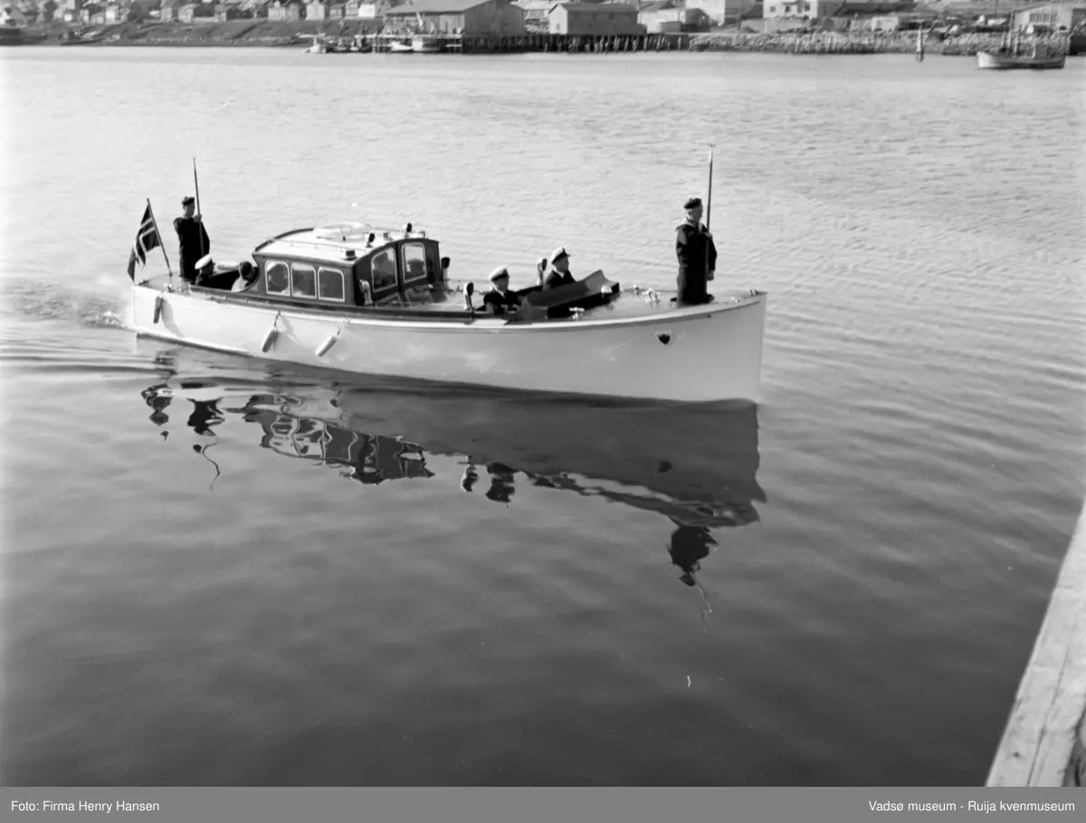Vadsø. Kongebesøk i Vadsø 1950. Sjalupp på tur fra kongeskipet inn til land.
Kong Haakon og kronprinsfamilien besøkte Vadsø 25.-26.7.1950 i forbindelse med en større rundreise i Nord-Norge sommeren 1950. Under besøket sto "biltur gjennom byen" og "besøk på sykehuset" på programmet. Kilde: Det kongelige hoff, arkivet
