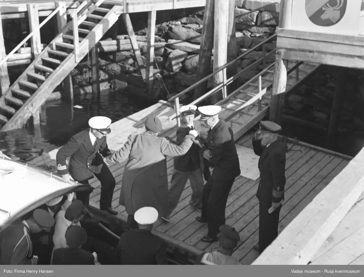 Vadsø. Kongebesøk i Vadsø 1950. En del av sjaluppen fra Kongeskipet helt i forgrunnen. Kvinnen som blir hjulpet fra sjaluppen ned på kaia er kronprinsesse Märtha.
Kong Haakon og kronprinsfamilien besøkte Vadsø 25.-26.7.1950 i forbindelse med en større rundreise i Nord-Norge sommeren 1950. Under besøket sto "biltur gjennom byen" og "besøk på sykehuset" på programmet.            Kilde: Det kongelige hoff, Arkivet