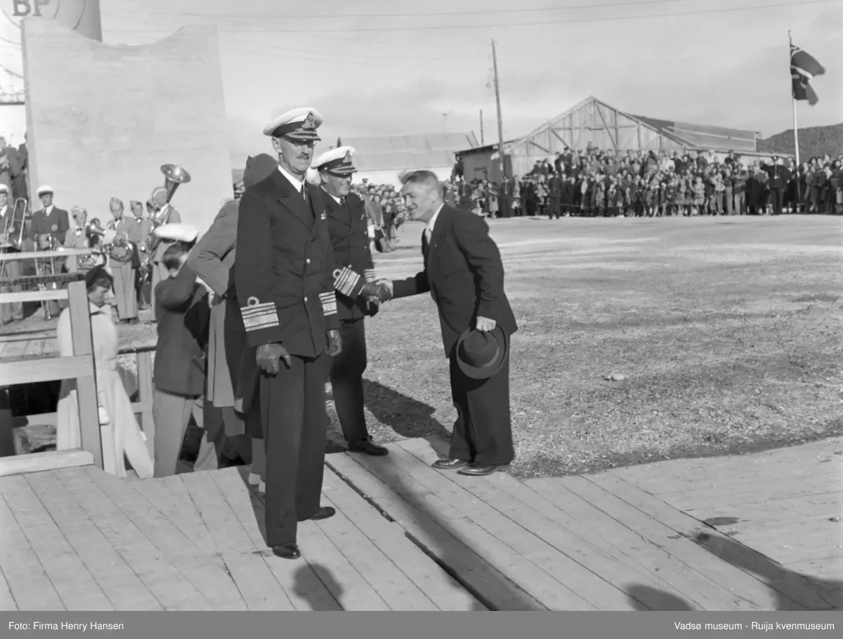 Vadsø. Kongebesøk i Vadsø 1950. Kronprins Olav hilser på fylkesmann Peder Holt, kong Haakon7. står foran. Prinsesse Astrid, Prins Harald og kronprinsesse Märtha på vei opp trappa.
Kong Haakon og kronprinsfamilien besøkte Vadsø 25.-26.7.1950 i forbindelse med en større rundreise i Nord-Norge sommeren 1950. Under besøket sto "biltur gjennom byen" og "besøk på sykehuset" på programmet. Kilde: Det kongelige hoff, arkivet