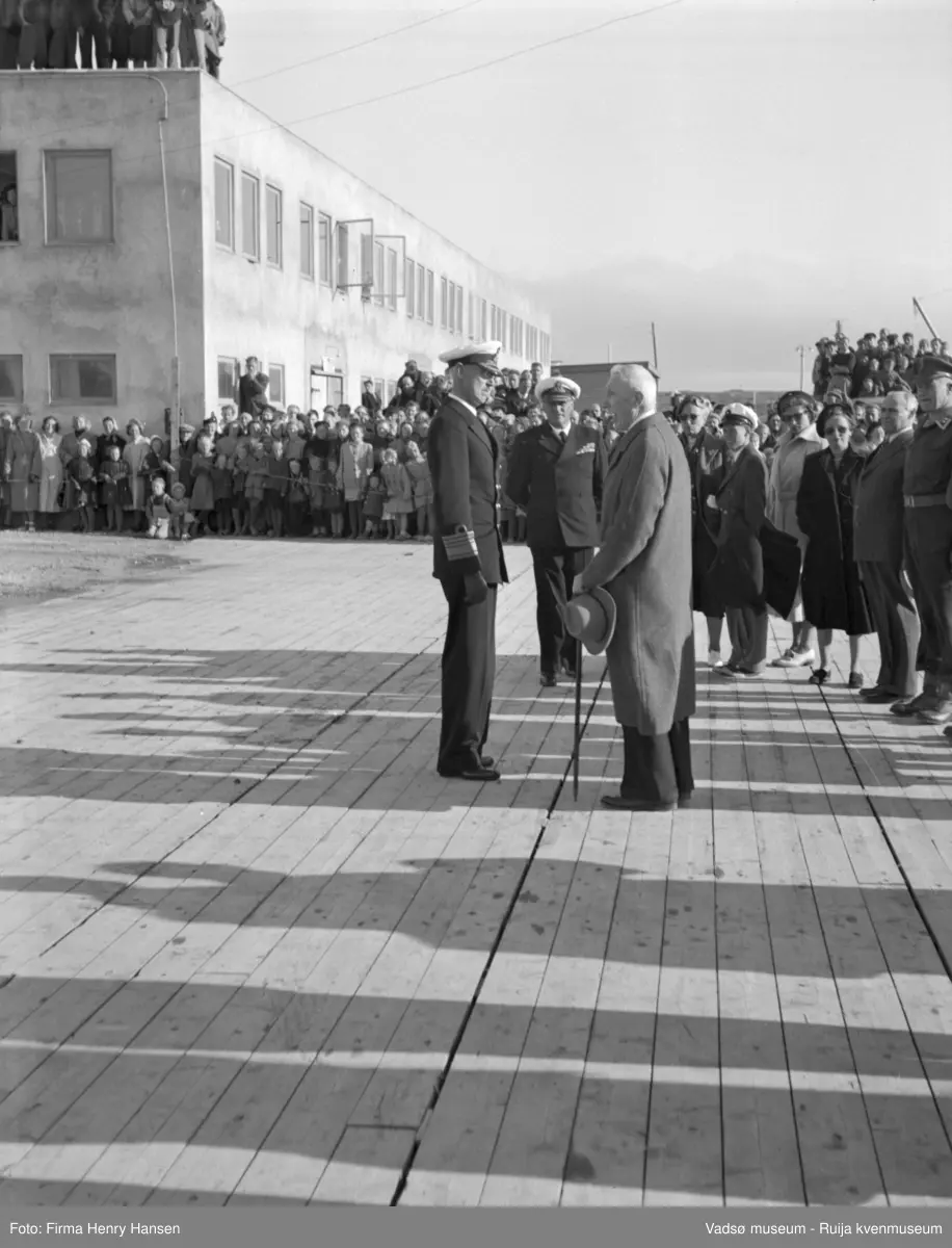 Vadsø. Kongebesøk i Vadsø 1950. Kongen og kronprinsfamilien blir tatt imot på kaia. Havnebygget i bakgrunnen.
Kong Haakon og kronprinsfamilien besøkte Vadsø 25.-26.7.1950 i forbindelse med en større rundreise i Nord-Norge sommeren 1950. Under besøket sto "biltur gjennom byen" og "besøk på sykehuset" på programmet. Kilde: Det kongelige hoff, arkivet
